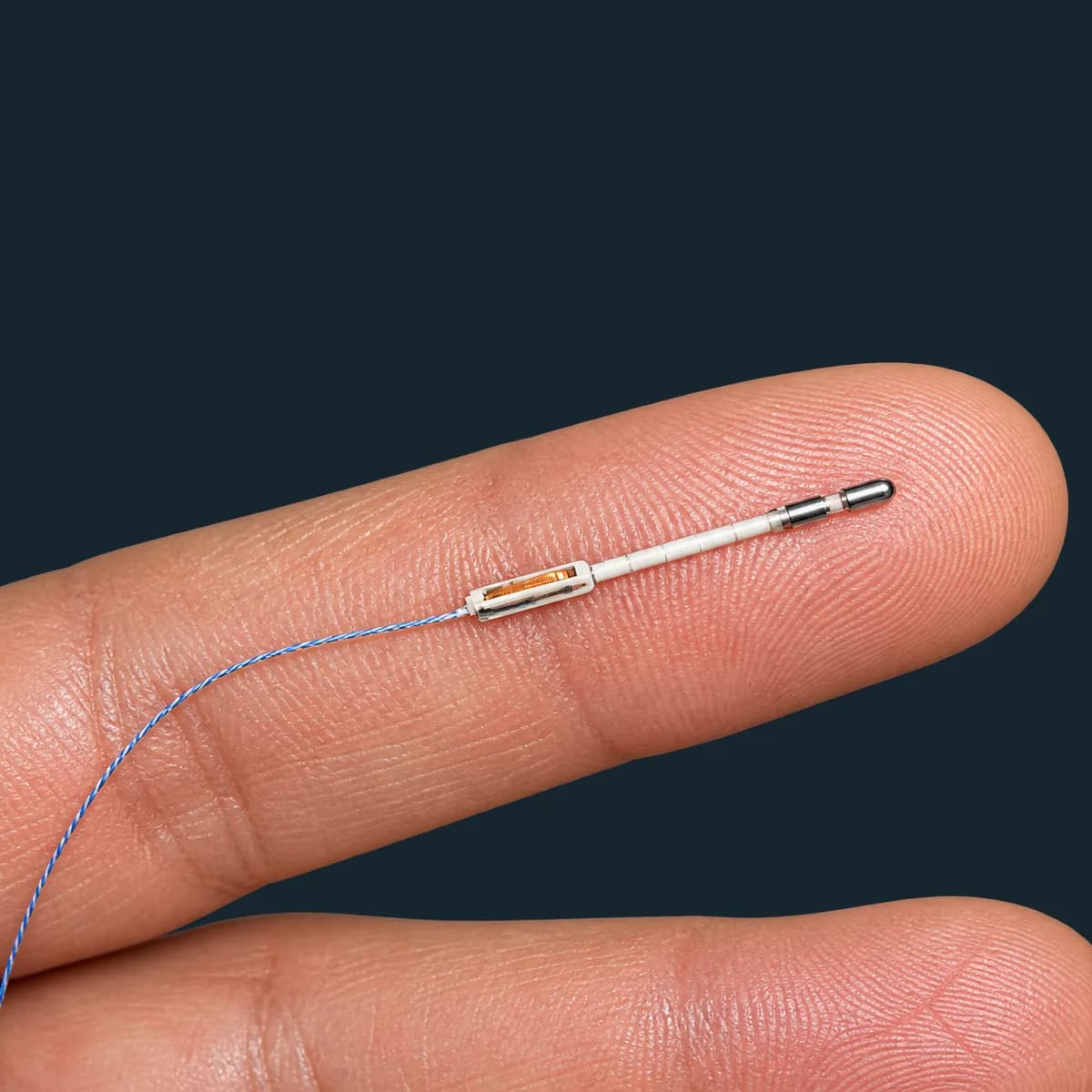 A peripheral nerve stimulation lead resting on a fingertip for scale